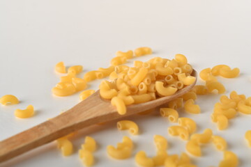 uncooked elbow macaroni on a white background.
