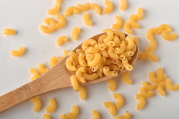 uncooked elbow macaroni on a white background.
