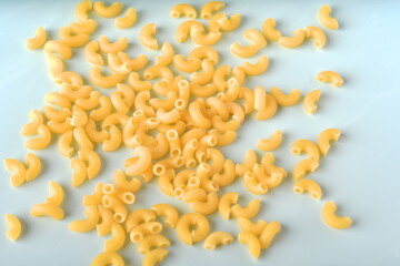 uncooked elbow macaroni on a white background.
