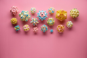 Set of multicolor handmade modular origami balls or Kusudama Isolated on pink background. Visual art, geometry, art of paper folding, paper crafts. Top view, close up, selective focus, copy space.