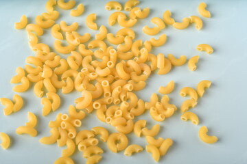 uncooked elbow macaroni on a white background.
