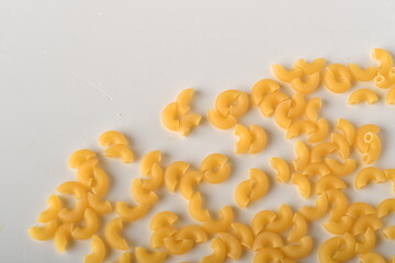 uncooked elbow macaroni on a white background.

