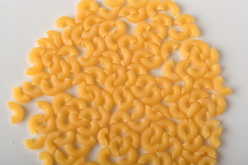 uncooked elbow macaroni on a white background.
