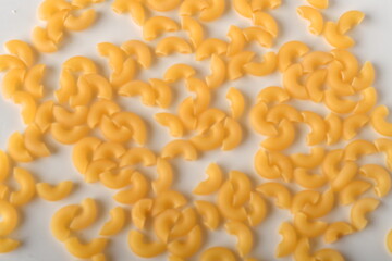 uncooked elbow macaroni on a white background.
