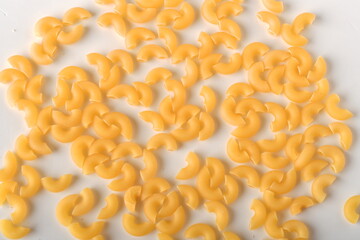 uncooked elbow macaroni on a white background.
