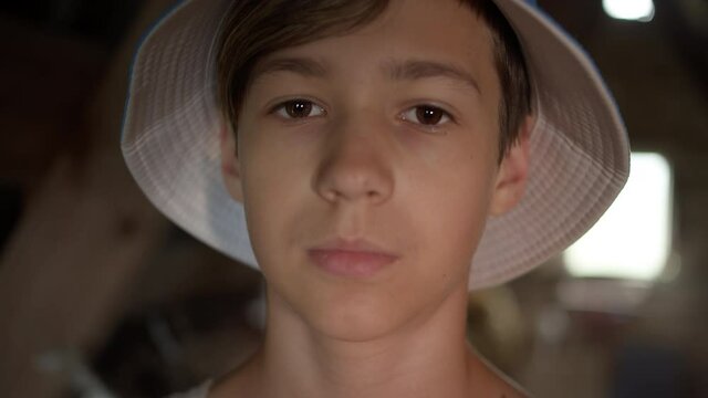 portrait of a sad serious boy in hat looking at the camera, indoors, whiny