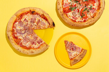 two ready-made pizzas and one slice on a yellow background