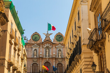 Fototapeta na wymiar Italy, Sicily, Trapani Province, Trapani. Clock tower with the Italian flag in the city center of Trapani.
