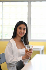 Portrait of young asian woman holding ice coffee cup and smiling to camera.