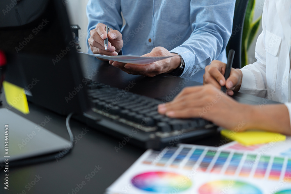 Poster graphic designer team working on web design using color swatches editing artwork using tablet and a 