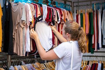 woman chooses clothes going through the broadcaster in the store at the market