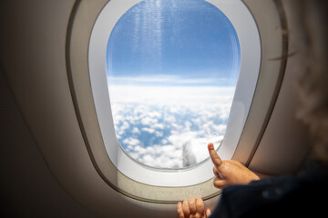 cute toddler points his finger at the sky through the window. first flight concept, traveling with children.