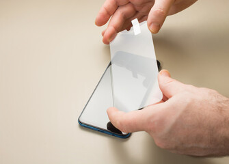 top view of installation of protective cover film on the smartphone. Maintenance support and repairing service concept.