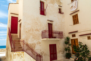 Fototapeta na wymiar Italy, Apulia, Metropolitan City of Bari, Monopoli. Red doors and railings on a stucco building.