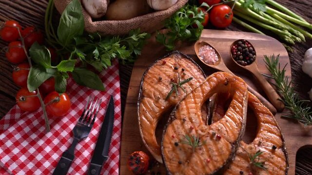 salmon fish steak with herbs and vegetables on wooden background