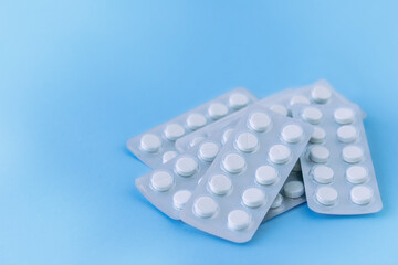 White pills in packaging on blue background, medicine background