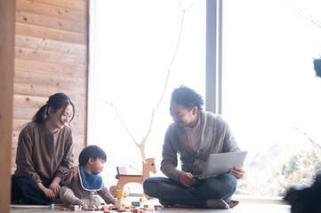 木造のきれいな新築の広い部屋で美人なママと家族団らんの幸せな若いファミリー　右にコピースペースあり	