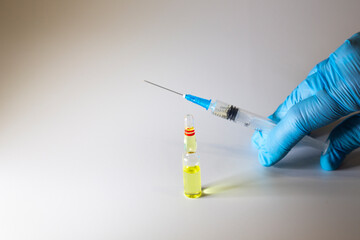syringe with medicine in the hand of a doctor in a blue glove and a bottle of medicine,