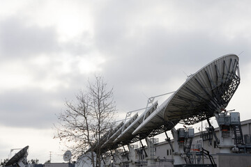 Satellite dishes lined up in a row on a cloudy day.