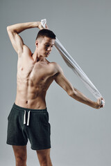 Fototapeta premium sporty man in black shorts holding towels behind his head pumped up press gym
