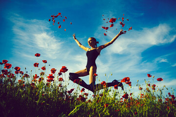 Beauty girl enjoying nature on poppy. Teenage model girl jumping on blooming wild flowers field. Free Happy Woman