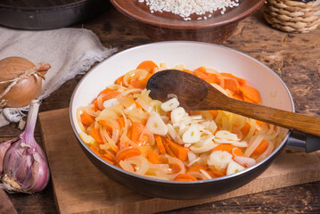 Cooking the base for soup from onions, carrots, garlic and tomatoes in a pan