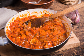 Cooking the base for soup from onions, carrots, garlic and tomatoes in a pan