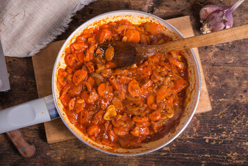 Cooking the base for soup from onions, carrots, garlic and tomatoes in a pan