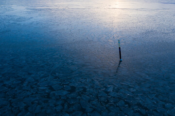 Aerial view of lone buoy and ice chunks in calm sea