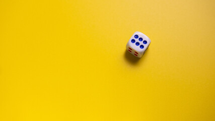 White dice with round dots number six on yellow background close-up. Concept of gambling and chance