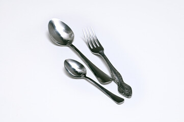 Two spoons and a fork on a white background. Image with selective focus.