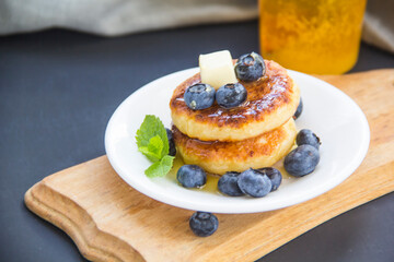 A healthy breakfast of pancakes, berries, butter, and honey
