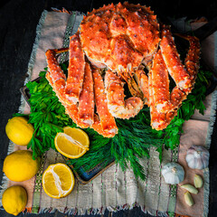Tasty king kamchatka crab with lemon slices on wood board