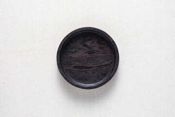 Dark black handmade round wooden plate on burlap. Round tray. 
