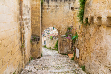 Italy, Basilicata, Province of Matera, Matera. Stone steps between stone buildings leading to an arch.
