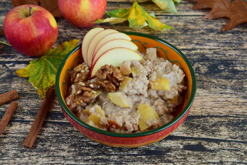 Spiced cinnamon apple pie porridge with walnuts. Wooden background