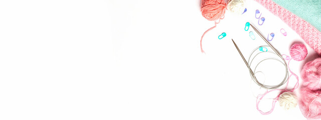 Accessories for knitting. Pink yarn skein, knitting needles, closeup on a white background. Copy space. Top view, needlework concept. banner