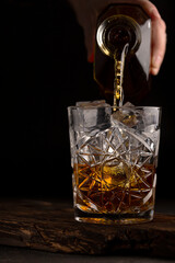 Whiskey or cognac is poured into an old fashioned glass, close up