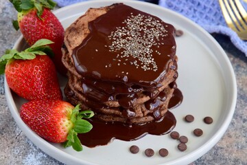 Double chocolate pancakes with fresh strawberries, chia seeds and chocolate sauce