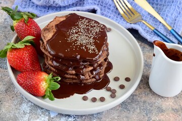 Double chocolate pancakes with fresh strawberries, chia seeds and chocolate sauce