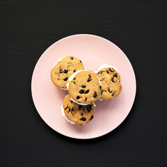 Homemade Chocolate Chip Cookie Ice Cream Sandwich on a pink plate on a black background, top view. Overhead, from above, flat lay.