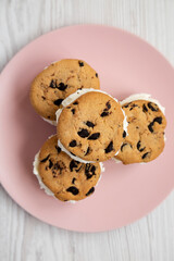 Homemade Chocolate Chip Cookie Ice Cream Sandwich on a pink plate on a white wooden background, top view. Overhead, from above, flat lay.