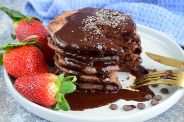 Double chocolate pancakes with fresh strawberries, chia seeds and chocolate sauce