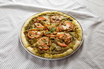 Homemade Pesto Pizza with Fresh Tomatoes and Mozzarella on cloth, low angle view.