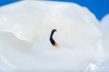 A burnt white, thick candle with molten paraffin wax. Close-up blurred in soft focus at high...