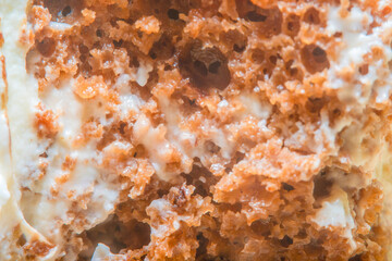 Background on the theme of cooking and dessert with dough soaked in cream. A closeup of a sliced piece of cake in soft focus.