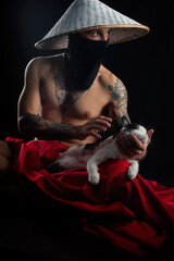 a naked slender samurai man in a red cape and an Asian hat with a cat in his hands
