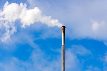 One Industrial smoke pipe from chimney on blue cloudy sky.