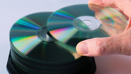 a man's hand puts a compact disc in a stack