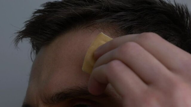 Injured man head with dry blood. Medical Treatment of wounds. Close-up. Take off antiseptic band-aid plaster. Close up, 4k footage.